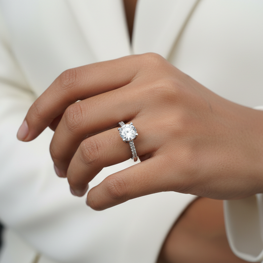 Close-up of a hand wearing a diamond ring with a blurred white background
