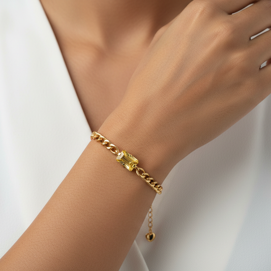 Gold bracelet with a yellow gemstone on a white background