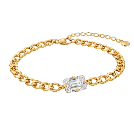 Gold chain bracelet with a diamond on a light gray background
