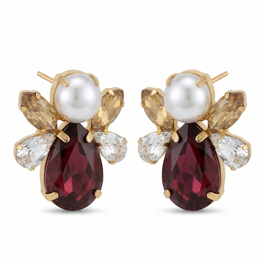 Pair of earrings with red gemstones and pearl-like centers on a white background