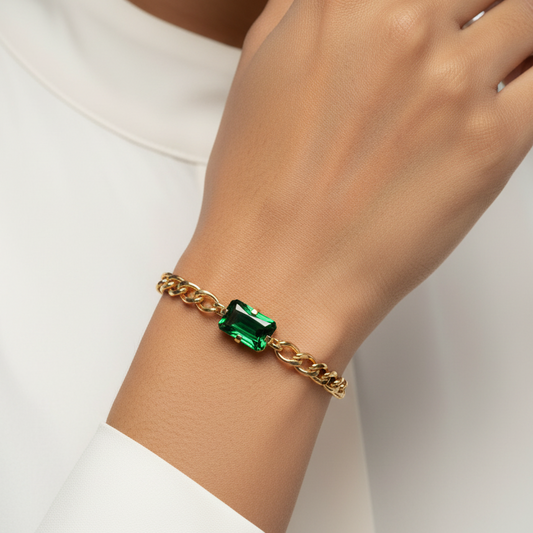 Gold bracelet with a green gemstone on a person's wrist against a white background