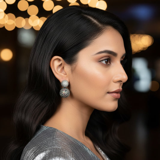 Close-up of a person wearing sparkling silver earrings outdoors.