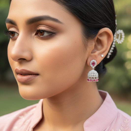 Close-up of a person wearing red and silver earrings outdoors.