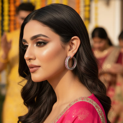 Close-up of a person wearing a silver hoop earring with pink gemstones.