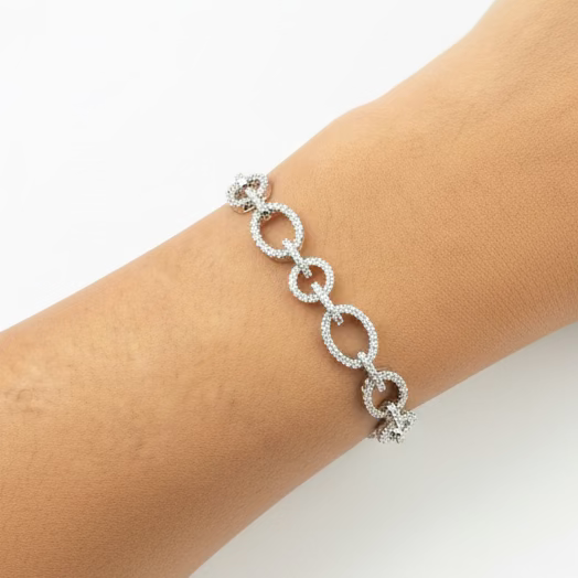 Silver bracelet on a wrist with a purple fabric background