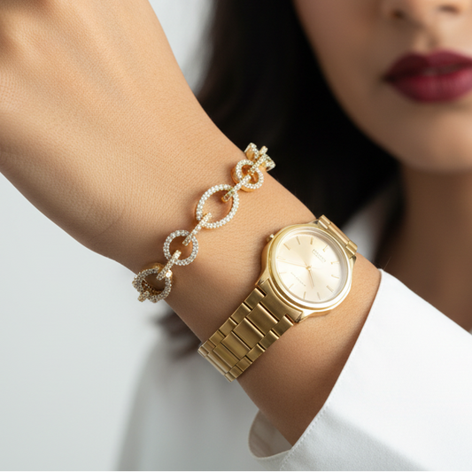 Woman wearing a gold watch and bracelet on a plain background