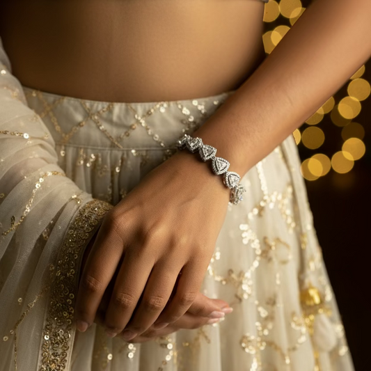 Bracelet with triangle-shaped gemstones on a wrist against a purple fabric background