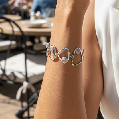 Silver hoop earrings on a wrist against a purple fabric background
