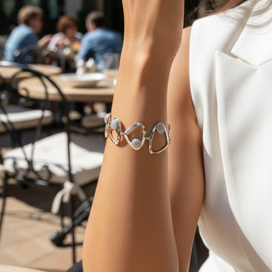Silver hoop earrings on a wrist against a purple fabric background
