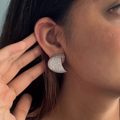 Woman wearing a silver earring in front of a mirror