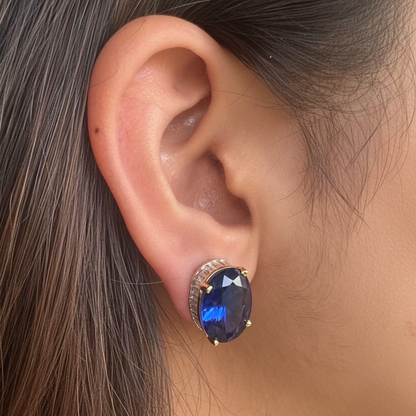 Close-up of an ear wearing a decorative earring with a purple gemstone.
