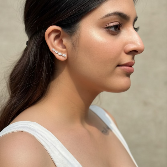 Woman wearing tortoiseshell sunglasses with a white top and visible tattoo.