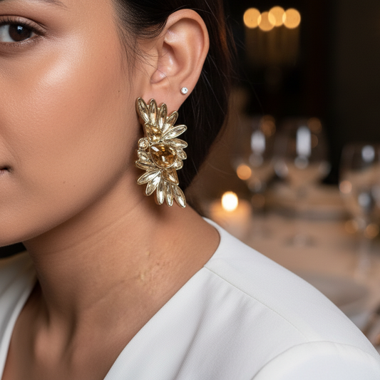 Close-up of a woman wearing gold earrings with a blurred background of a dining table set for a formal event.