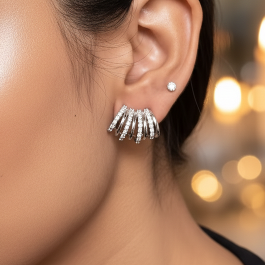 Close-up of a woman wearing silver earrings with a blurred candlelit background