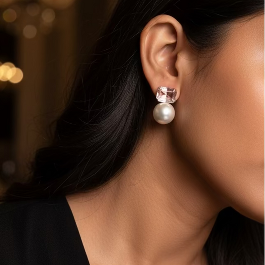 Close-up of a person wearing pearl earrings with a neutral background