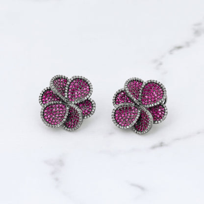 Pair of pink flower-shaped diamond earrings on a marble surface