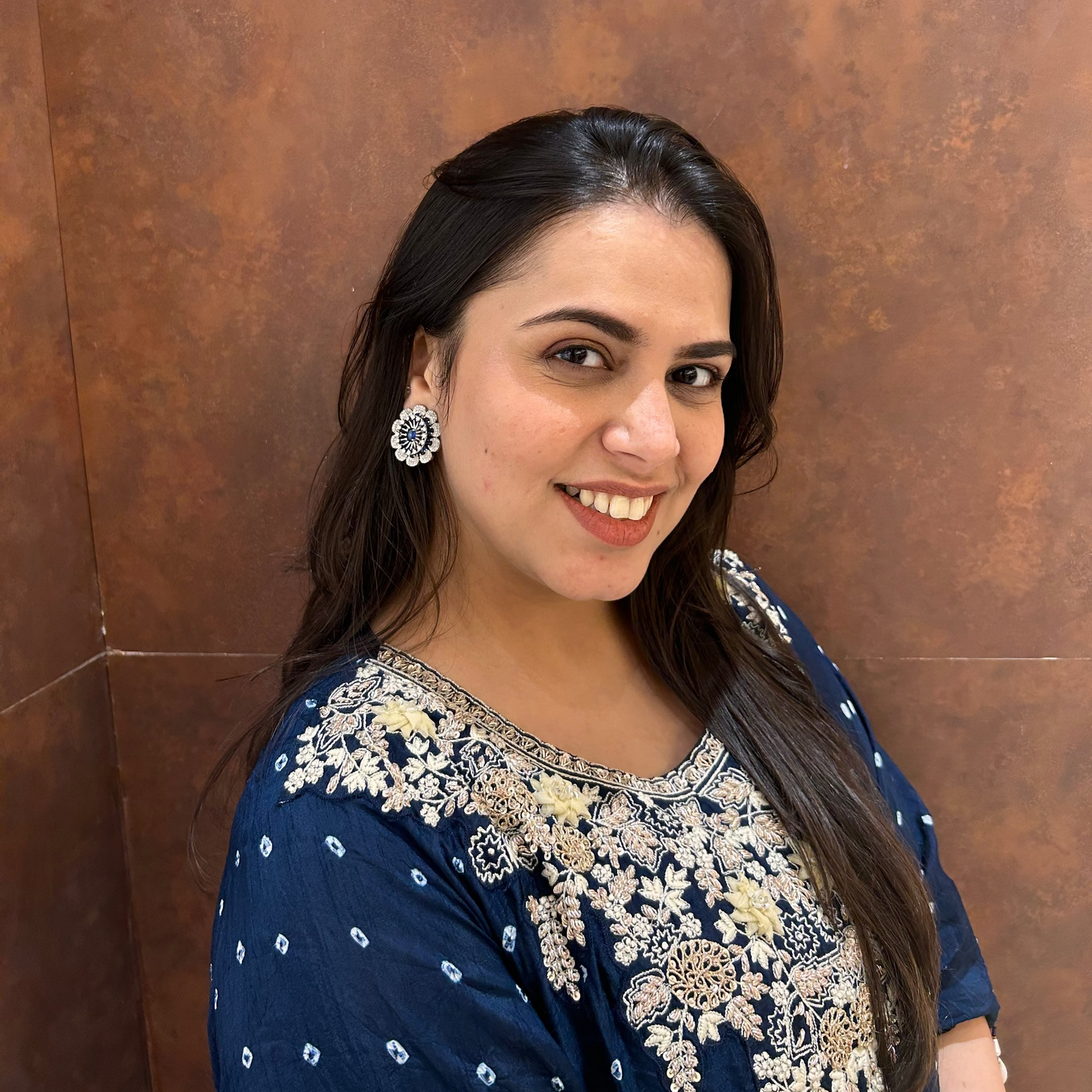 Woman wearing a blue and white traditional outfit against a brown wall