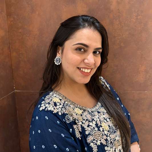 Woman wearing a blue and white traditional outfit against a brown wall