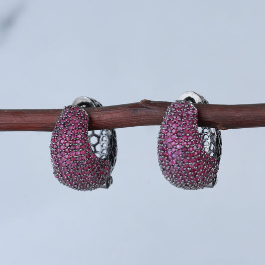 Pair of pink gemstone hoop earrings on a branch with a blurred background