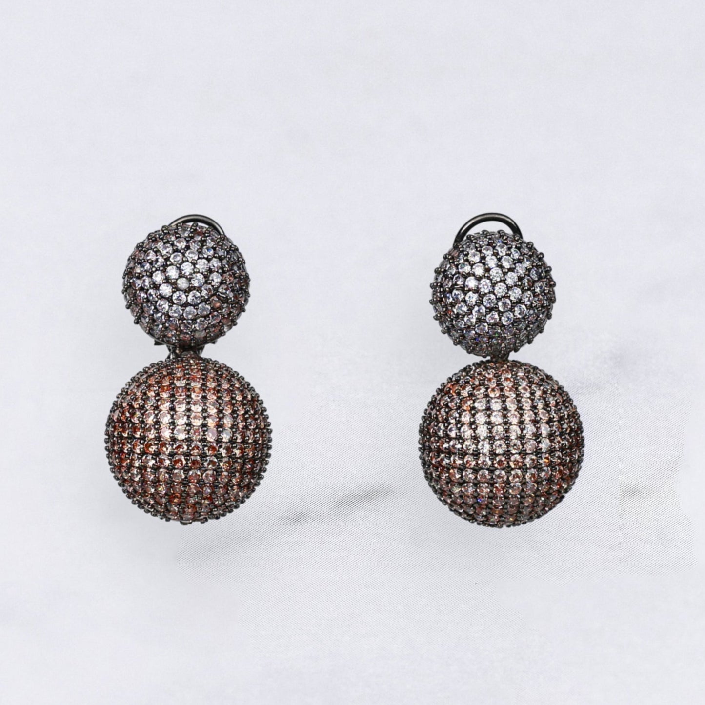 Pair of diamond earrings in champagne and silver colour on a marble surface