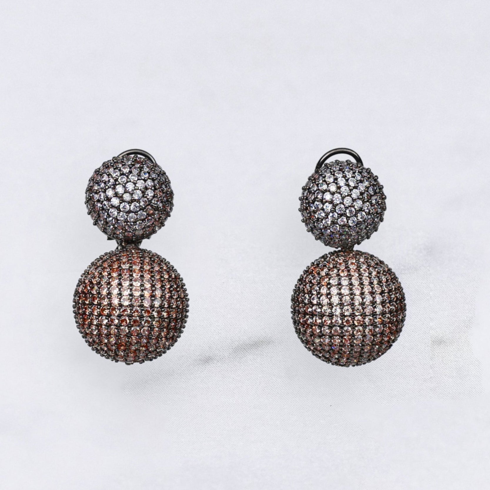 Pair of diamond earrings in champagne and silver colour on a marble surface