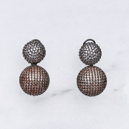 Pair of diamond earrings in champagne and silver colour on a marble surface