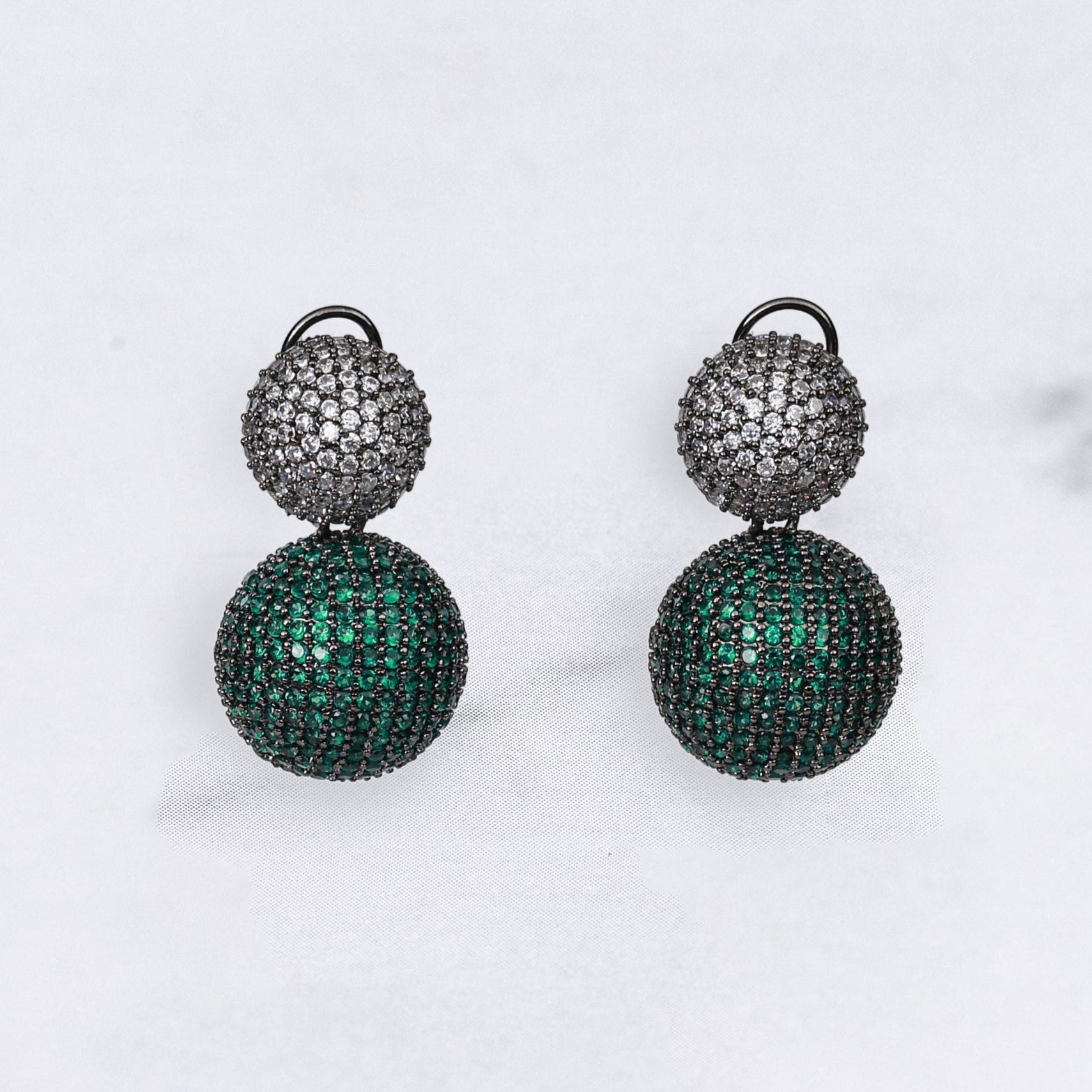 Pair of green and silver diamond earrings on a marble background