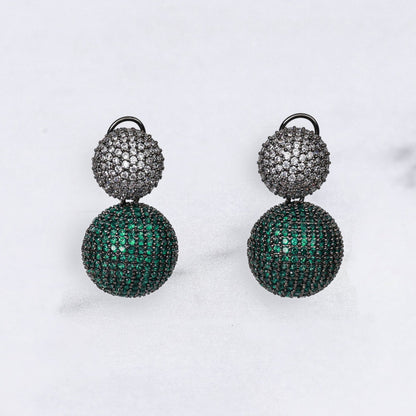 Pair of green and silver diamond earrings on a marble background