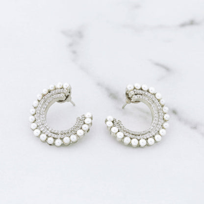 Silver hoop diamond earrings with pearl accents on a marble surface