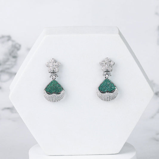 Pair of green diamond earrings on a white stand with a marble background