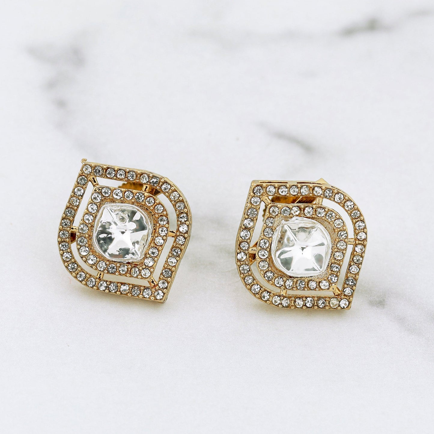 Pair of gold and crystal earrings on a marble surface