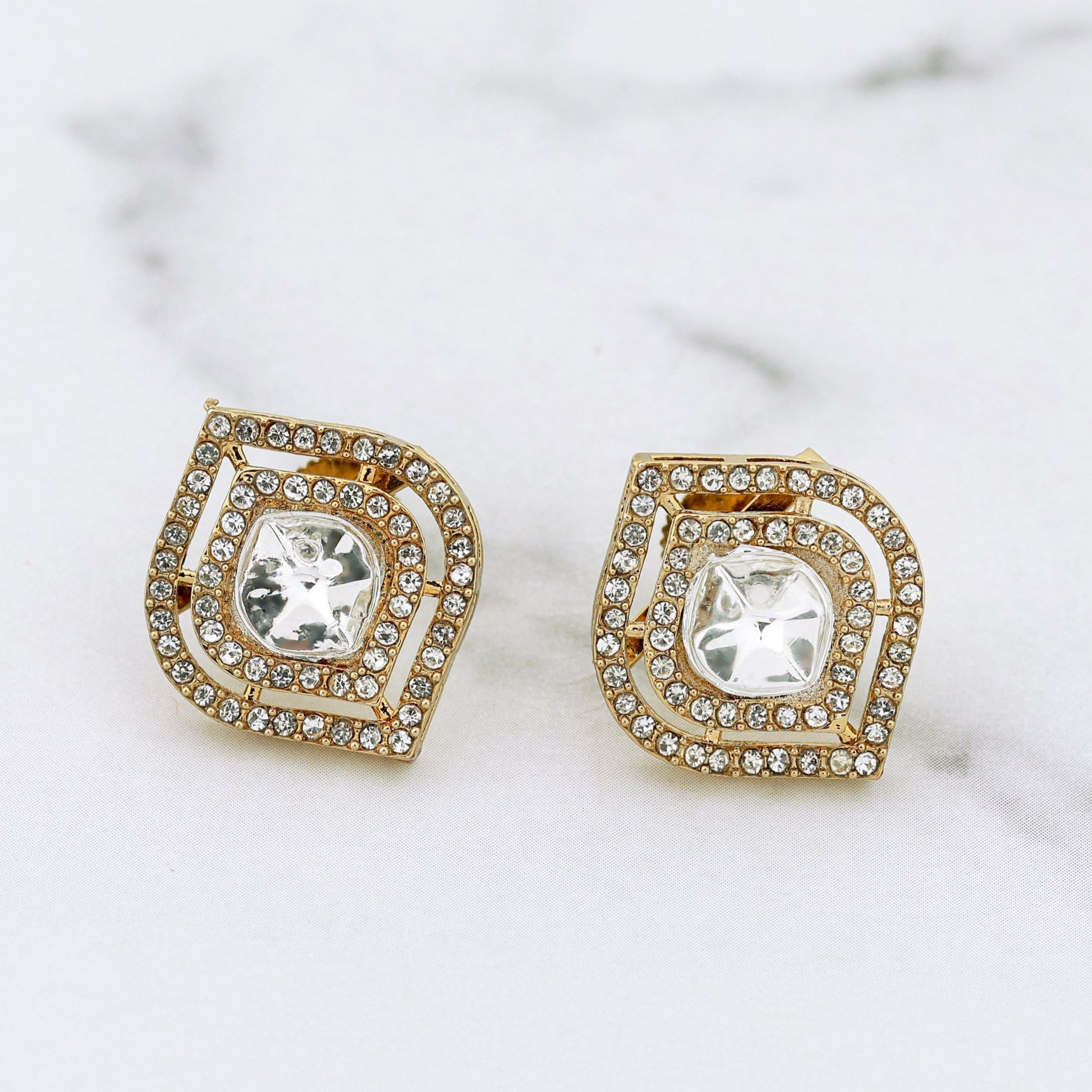 Pair of gold and crystal earrings on a marble surface