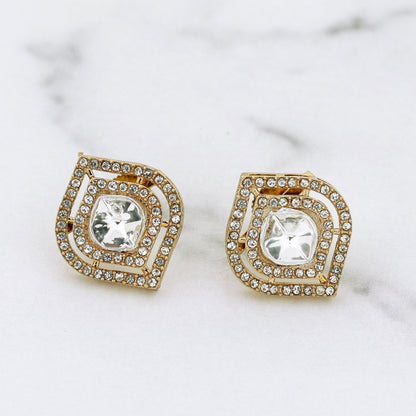 Pair of gold and crystal earrings on a marble surface