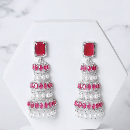 Pair of earrings with red and white stones on a marble background